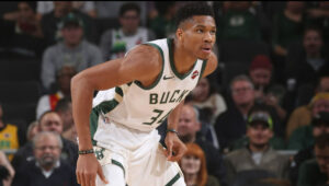 Giannis Antetokounmpo melakukan serangan dan bertahan dalam aksi pertandingan NBA modern secara dinamis.