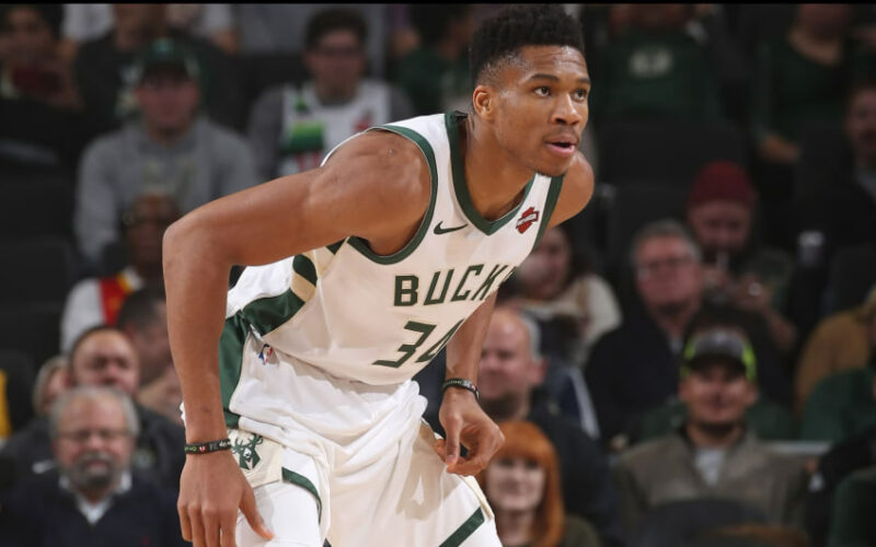 Giannis Antetokounmpo melakukan serangan dan bertahan dalam aksi pertandingan NBA modern secara dinamis.