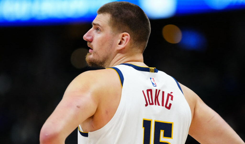 Ilustrasi Nikola Jokić sedang melakukan passing cerdas dalam pertandingan NBA.
